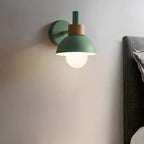 Green wall lamp on a white wall with a nightstand and items below.